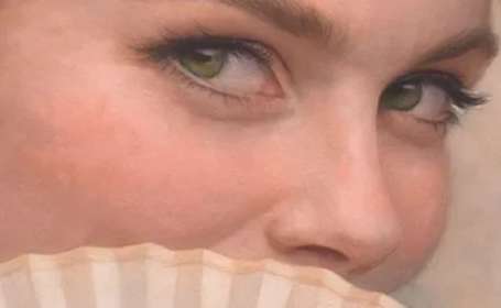 Close up of a lady's eyes overlooking the edge of a fan 