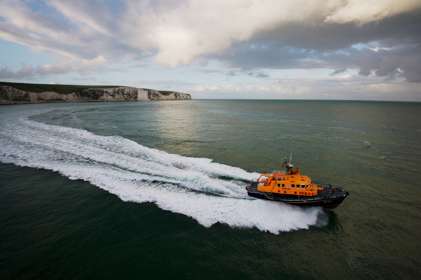 A lifeboat at sea with the white cliffs of Dover in the background
