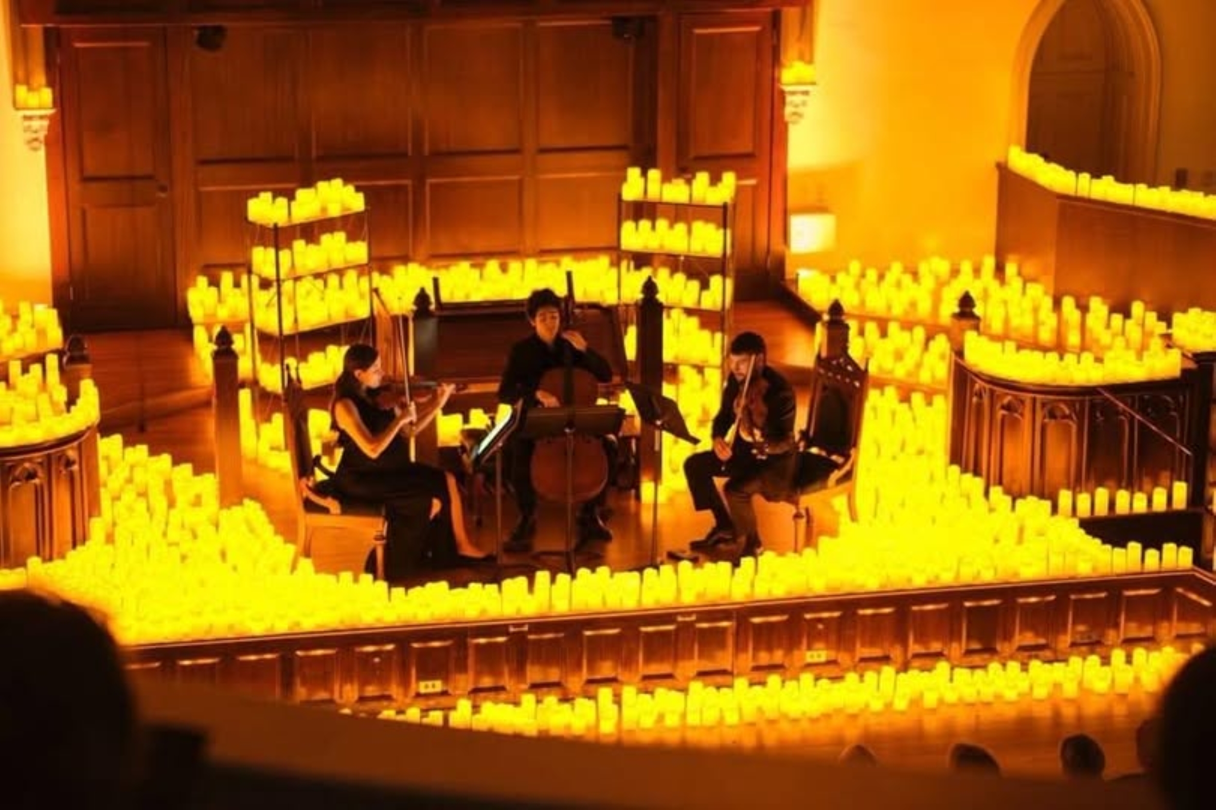 3 string musicians surrounded by lit candles