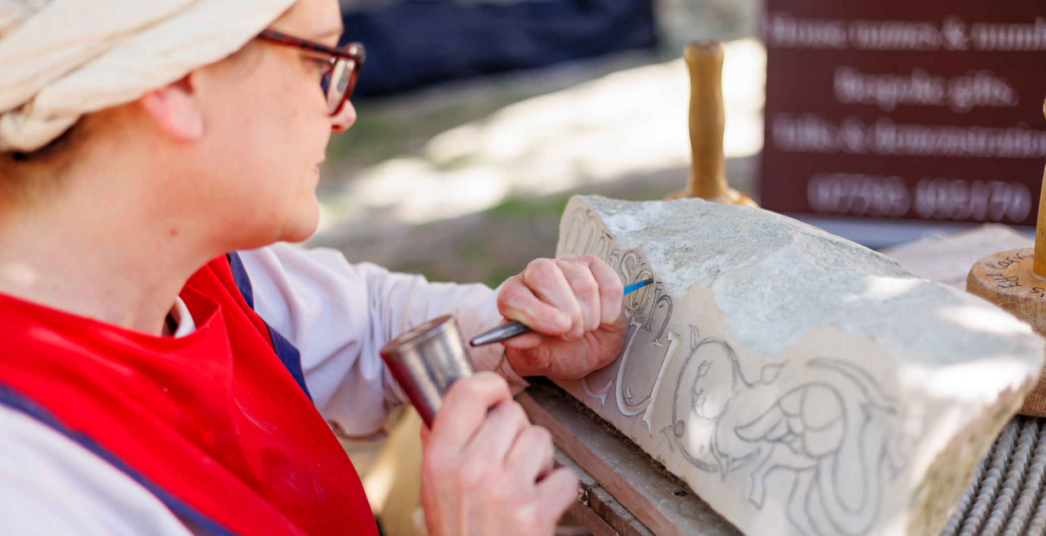 A person carving the Maison Dieu logo into stone