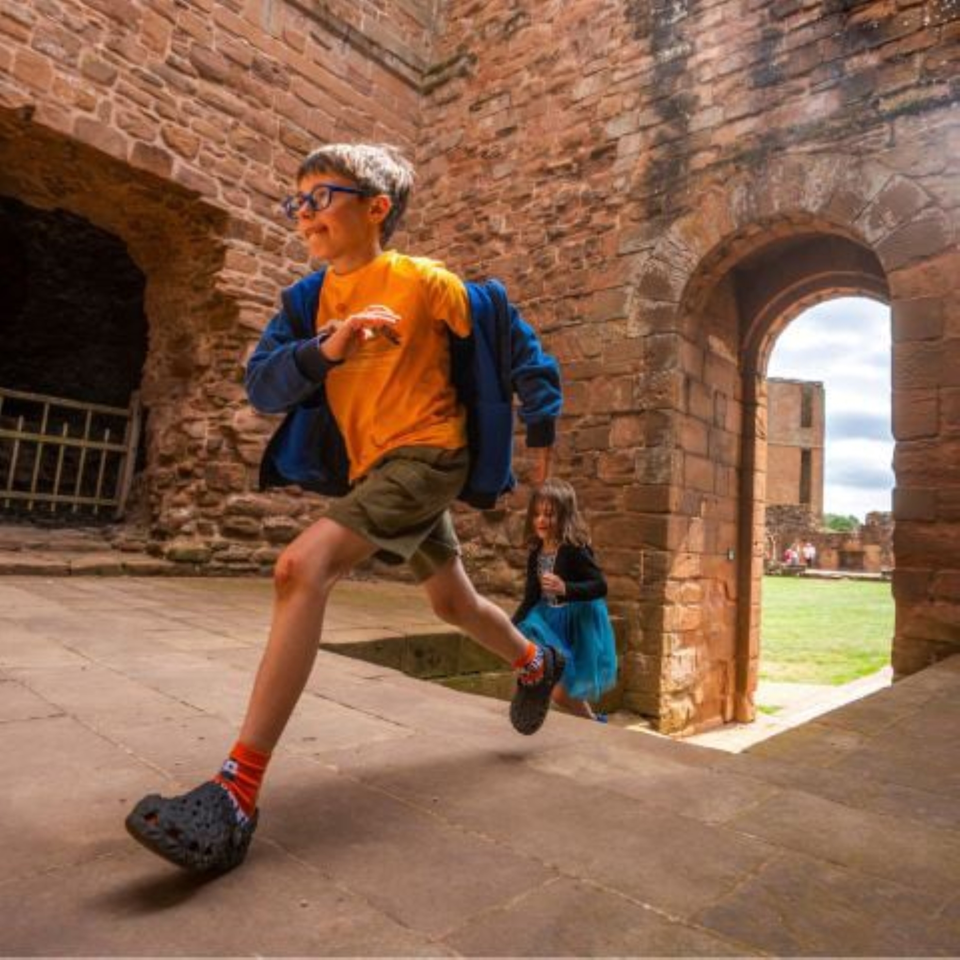 Boy and girl running through an ancient monument