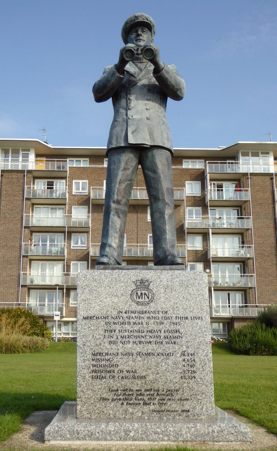 A statue of a man dressed in Merchant Navy uniform holding a pair of binoculars.