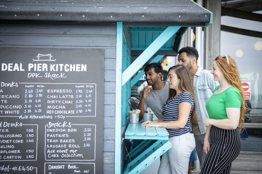 Four people buying snacks from an outdoor wooden shack.