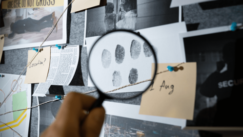 An evidence board with a magnifying glass over fingerprints