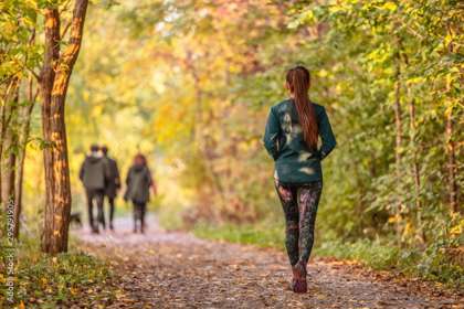 A woman walking along a woodland path, with 3 people and a dog ahead of her