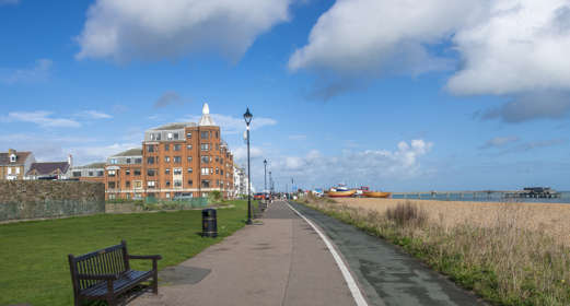 Deal promenade with fishing boats, benches, cycle lane and view of Deal Pier in the distance