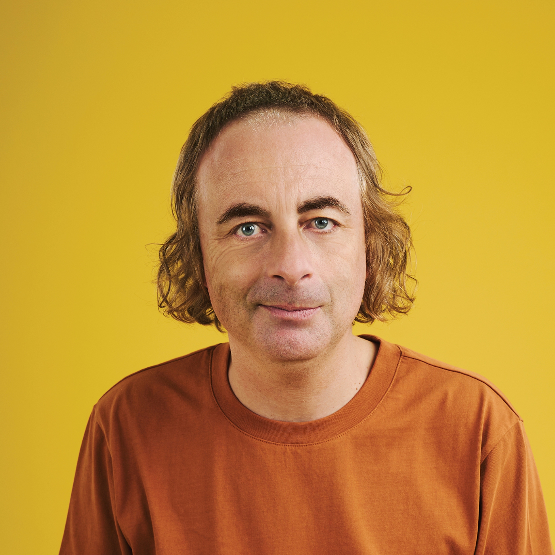 Head and shoulders of Paul wearing an orange t shirt