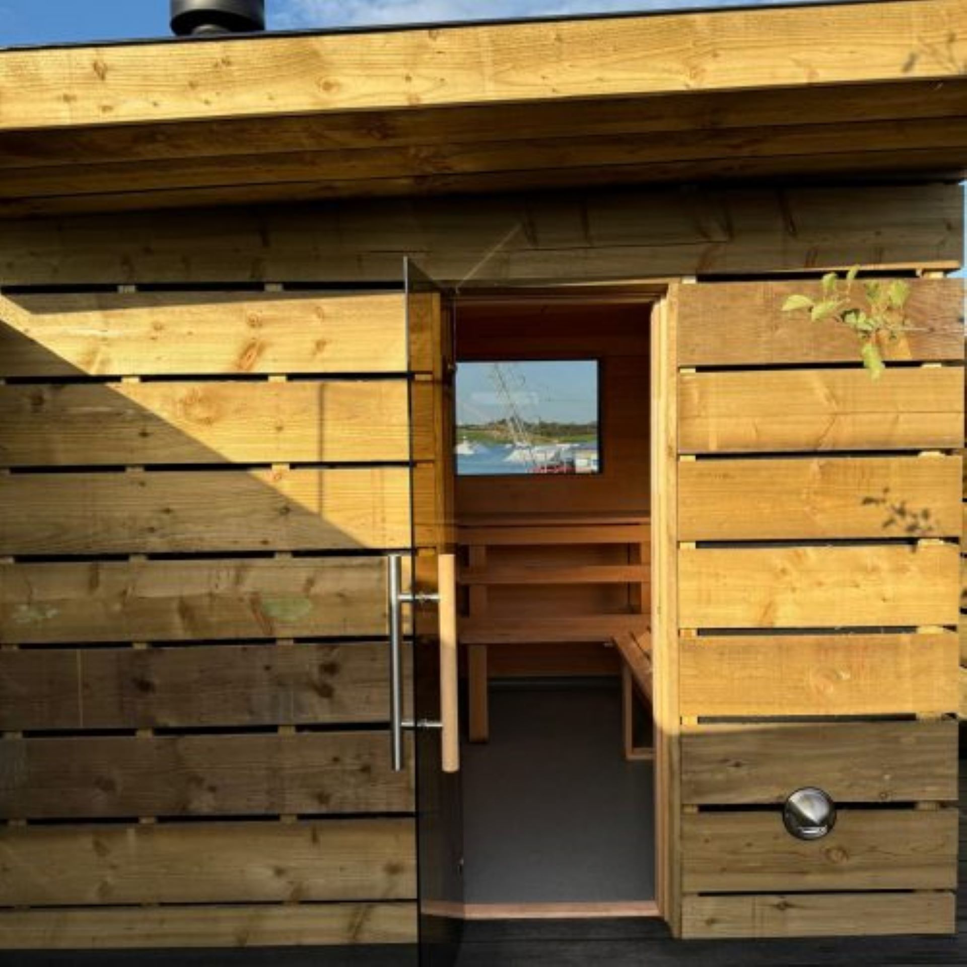 Wooden sauna cabin with window through to wake park