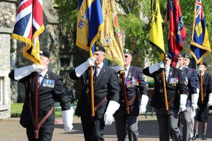 Image of retired servicemen parading with flags to commemorate VE Day 