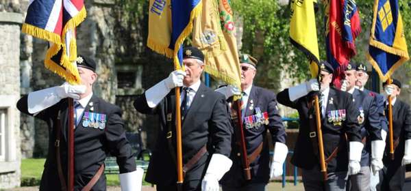 Image of retired servicemen parading with flags to commemorate VE Day 