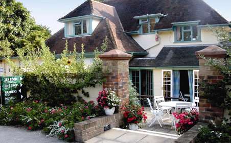 Exterior of the Pines Tea Room with white table & chairs on the patio area.