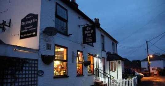 The white exterior of The Plough Inn at nightfall