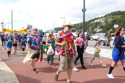 People walking on the seafront with the cliffs in the background