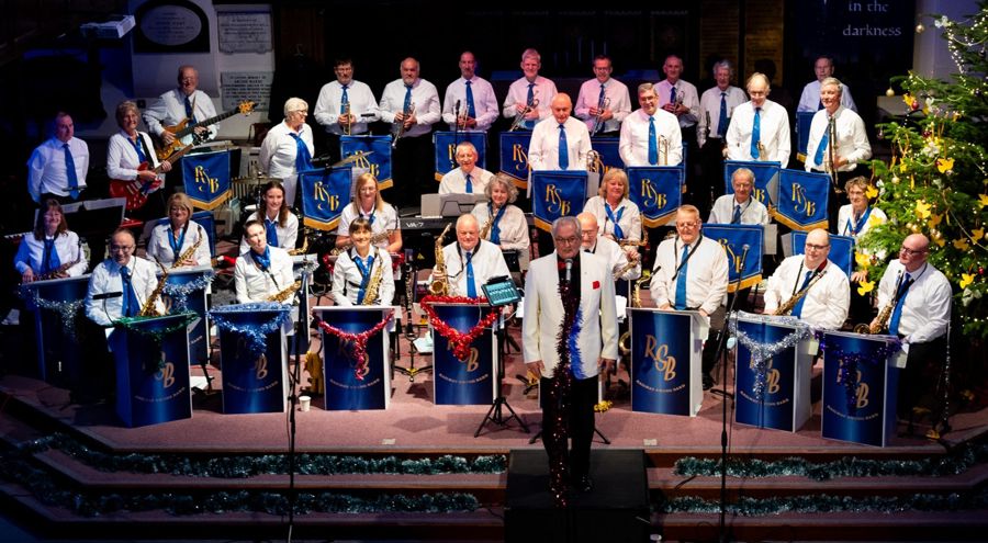 Railway Swing Band musicians playing on a stage in white shirts & blue ties.