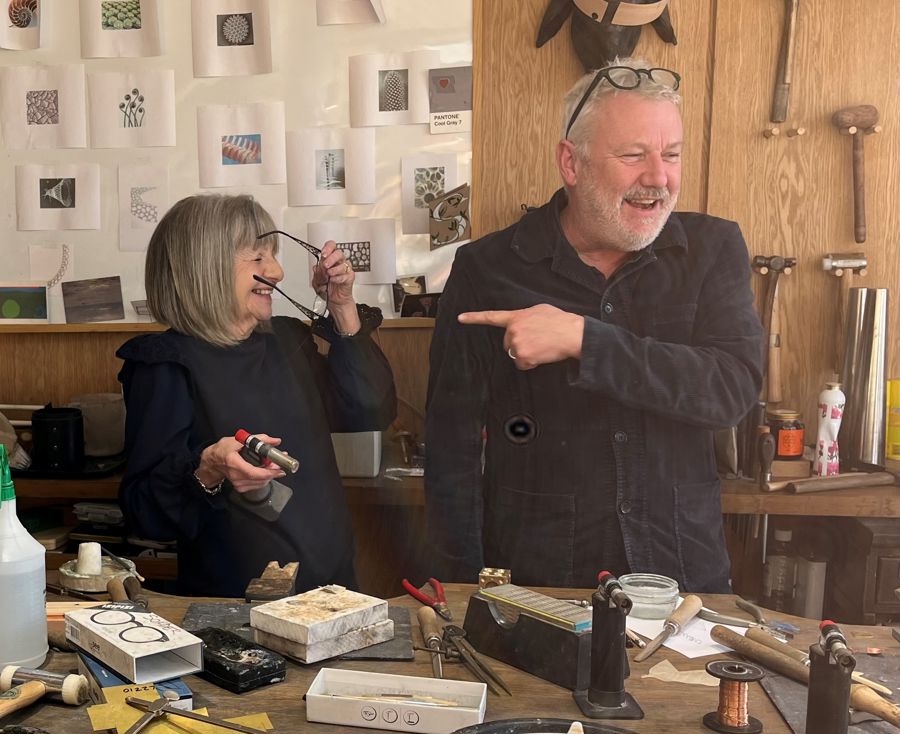 A man and a woman at a work bench with tools for making jewellery.