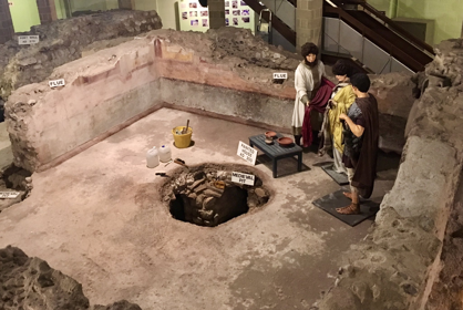 Mannequins in Roman costume stand amongst archaeological remains of the Roman Painted House