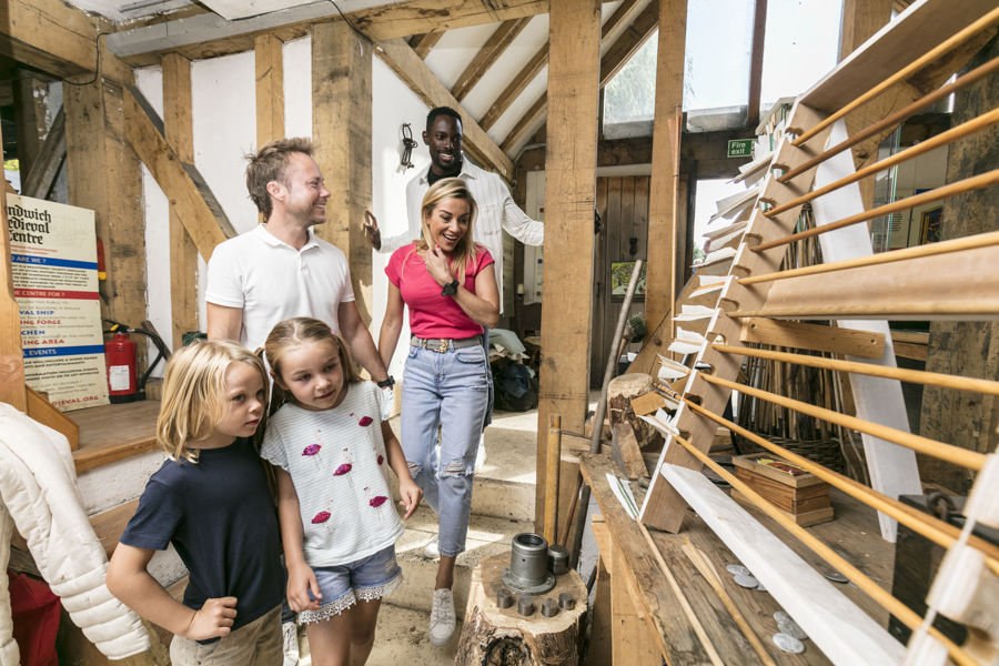 A family of three adults and two children looking at a display of wooden arrows.