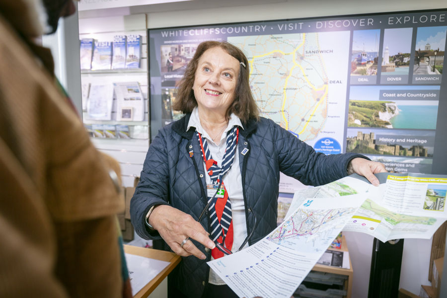 A female member of the visitor information team showing a map and guide to a visitor.