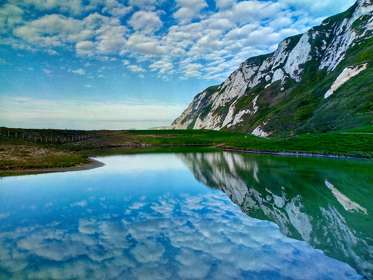 Chalk cliffs, blue sky and clouds reflected in a pool of water