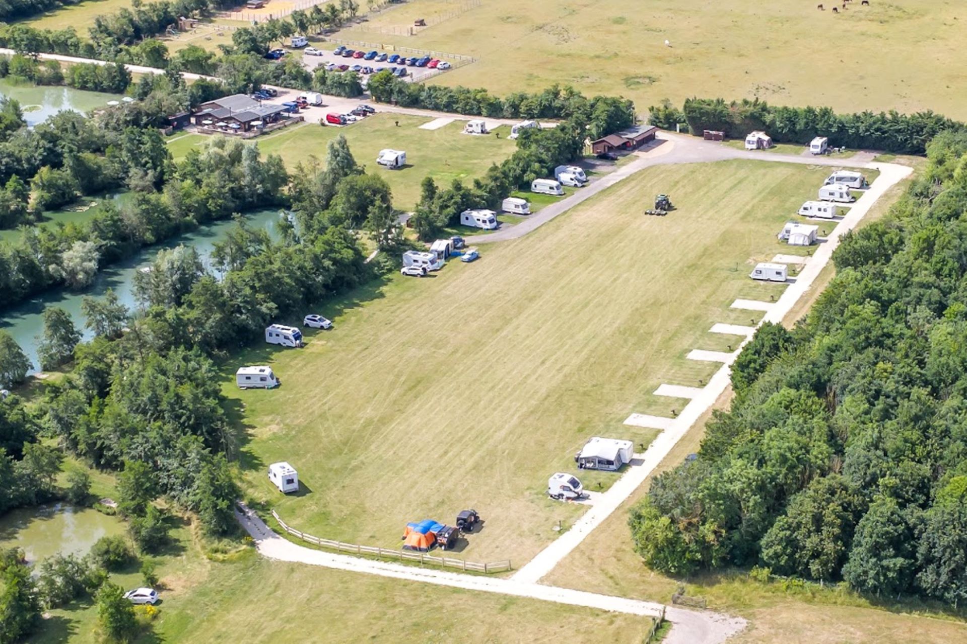 Aerial view of a field with caravans parked round the edge.