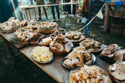 Plates of meat, bread and other Medieval style food on a wooden table.