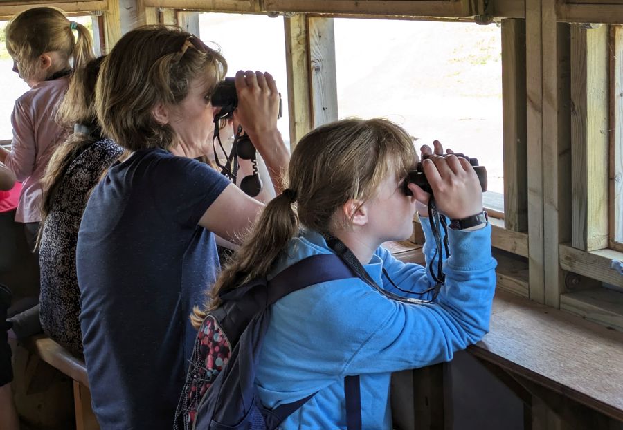 A family group with binoculars in a hide