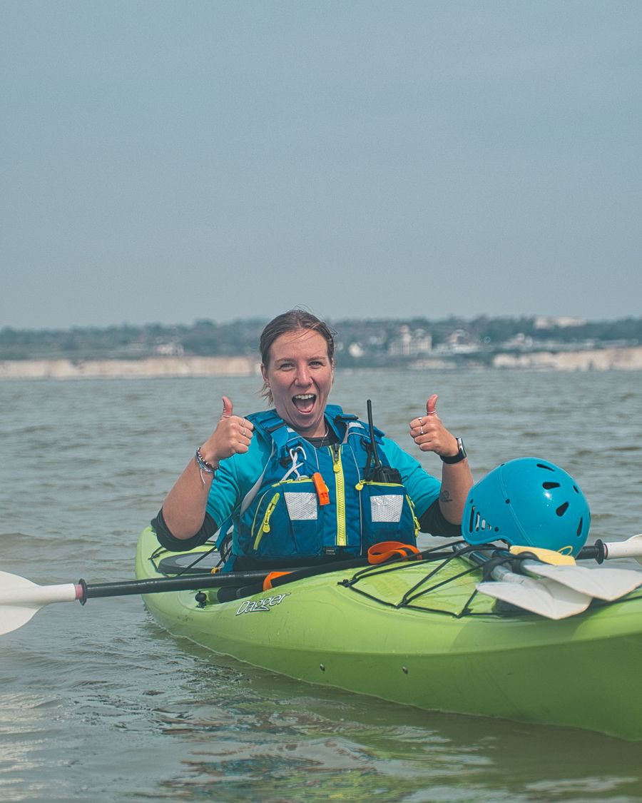 A woman in a sea kayak giving the thumbs up