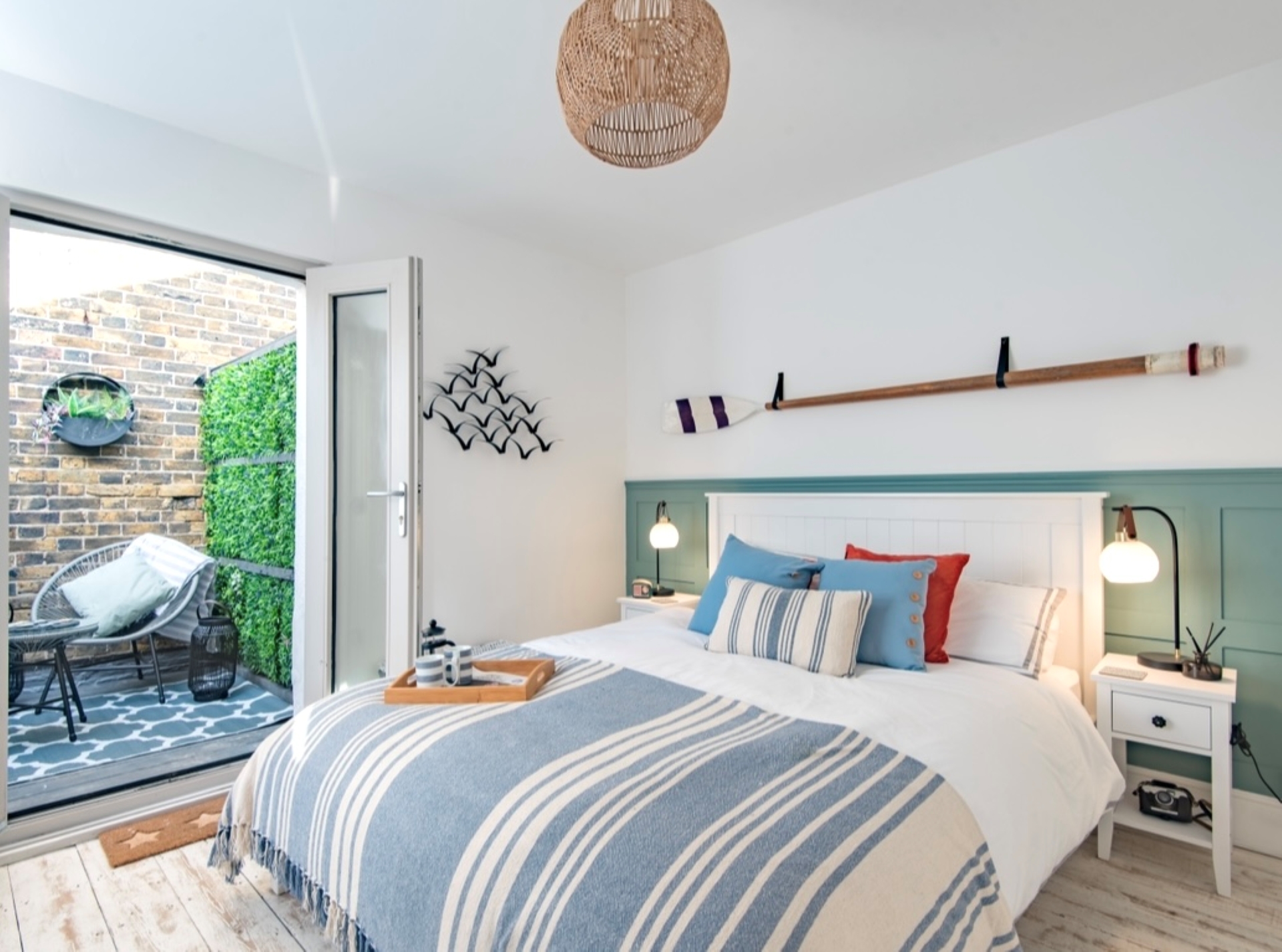 Double bed with 2 bedside cabinets & lamps, open patio doors to courtyard