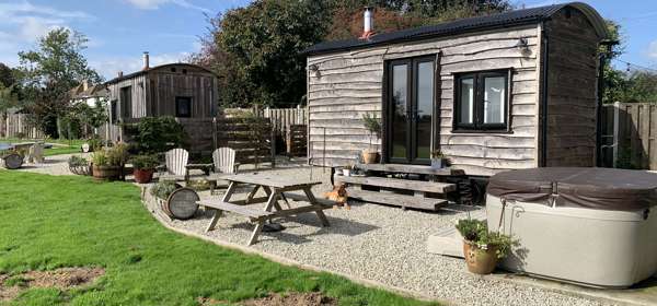 Outside view of Shepherds Huts at Spitfire Barn with seating area and hot tub