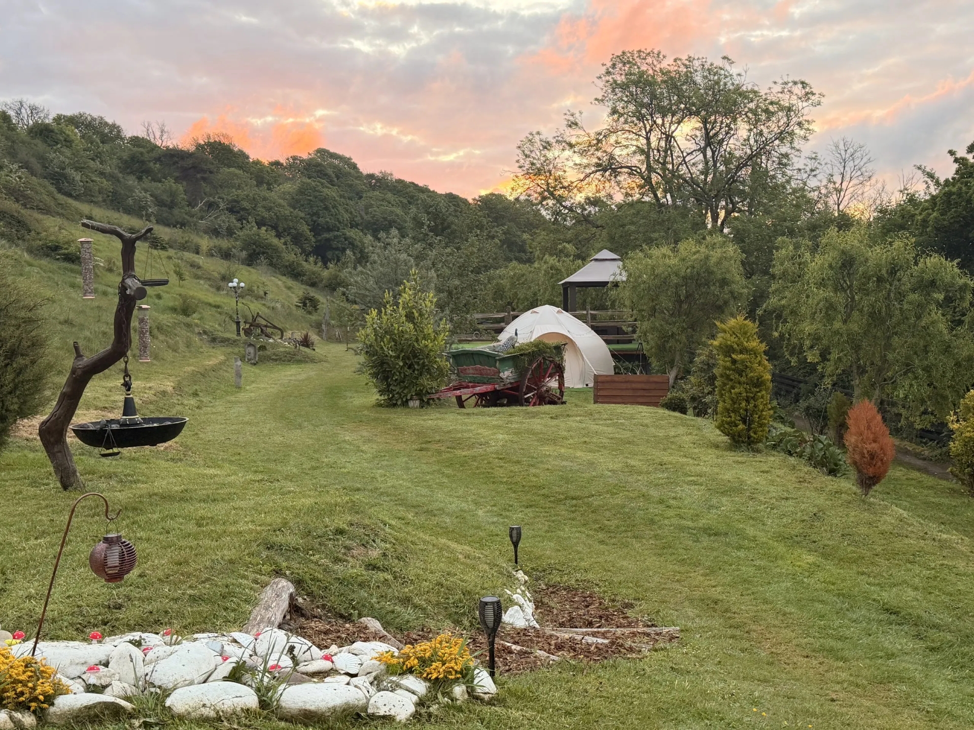 A cream glamping tent in green countryside surrounded by trees.