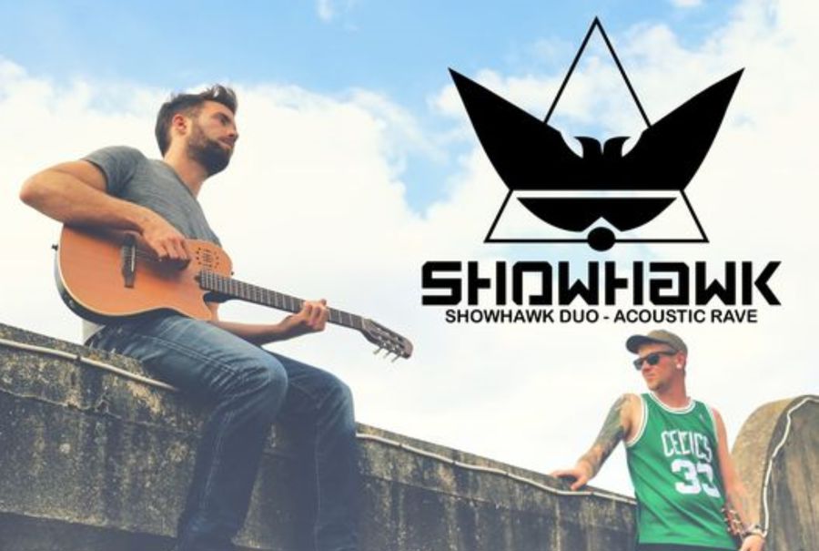 Musical Duo Showhawk with one sitting on a wall playing a guitar , the other standing.