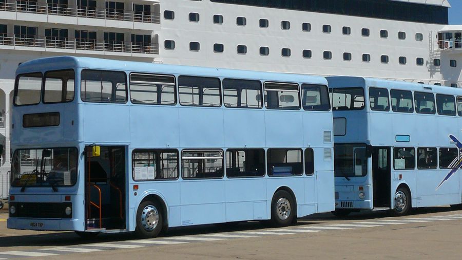 Two double-decker buses parked in front of a cruise ship docked in the Port of Dover.