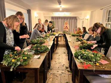 A group of ten women making Christmas wreaths