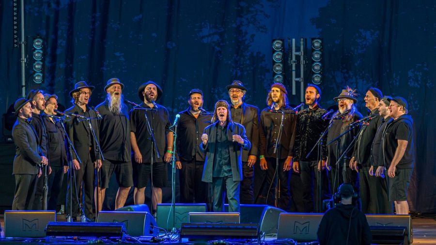 A large group of men dressed in black singing on a stage