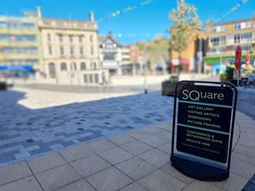 A metal sign with blurred buildings in the background