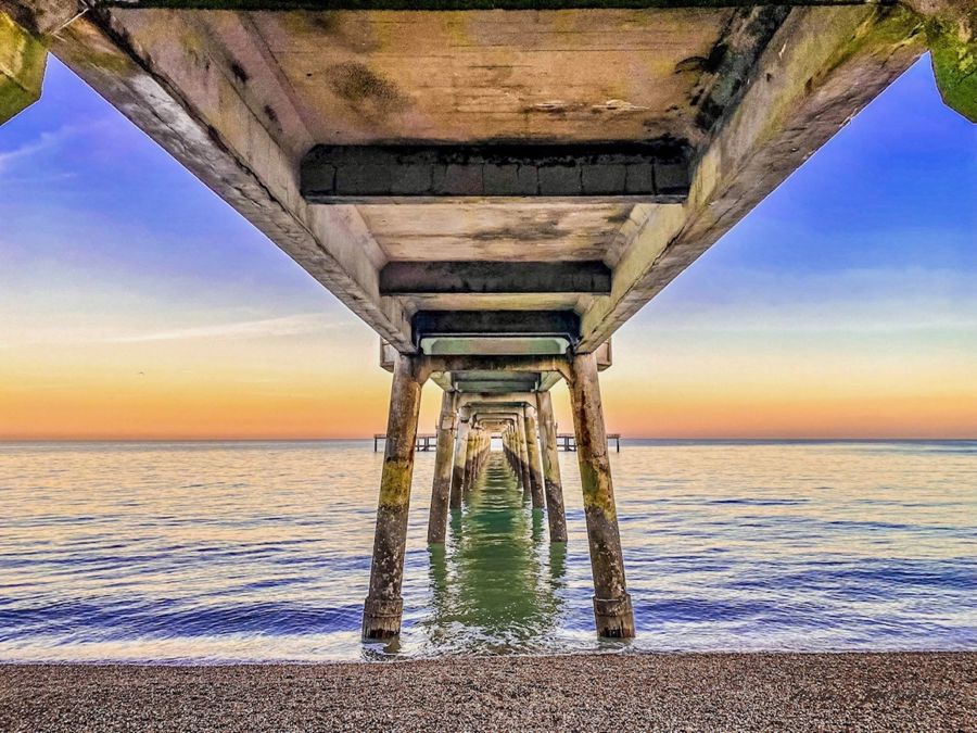 Deal Pier from below, looking along its legs out to sea. 