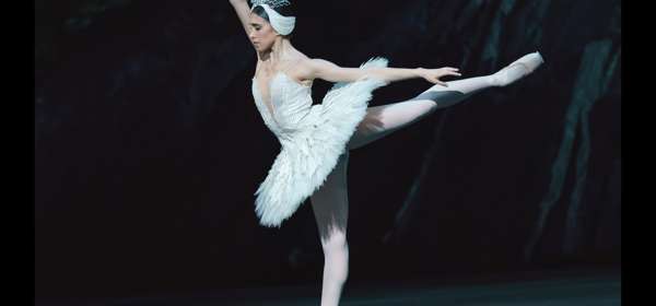 A ballerina dressed in white performing in Swan Lake