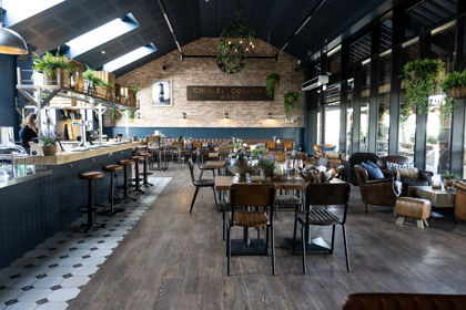 Interior of restaurant showing vaulted ceiling, bar area and seating areas.