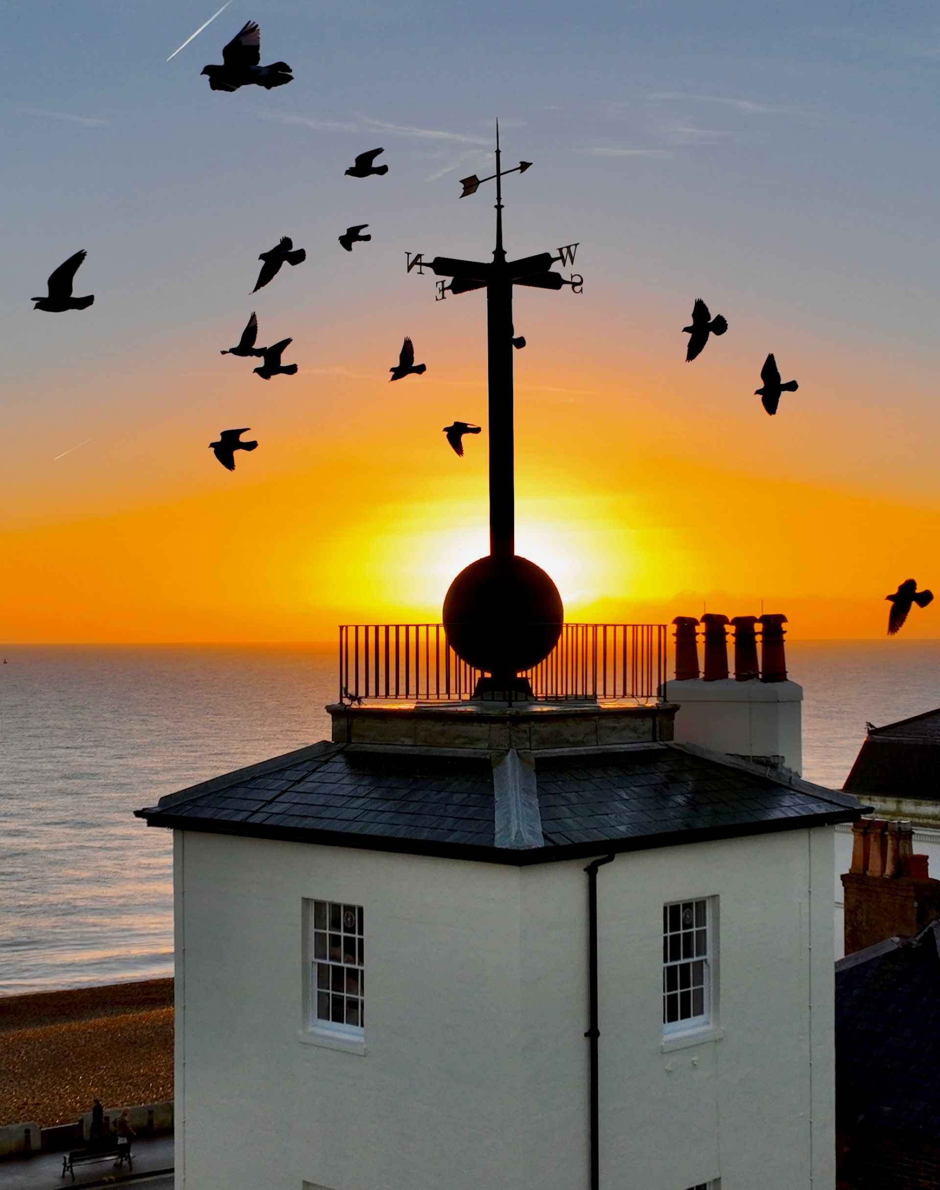 Building with sunrise in the background and birds in flight
