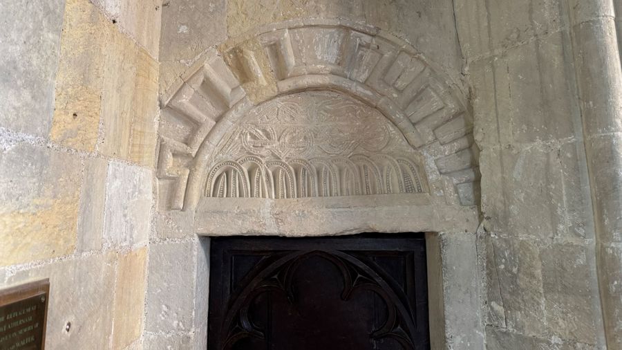Pale stone, arched, decorative carving above a doorway