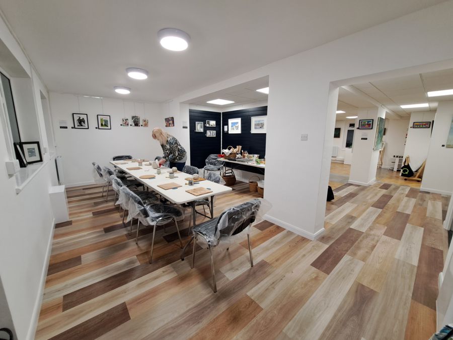 The interior of a room with wooden floor, and a large table for creative workshops.