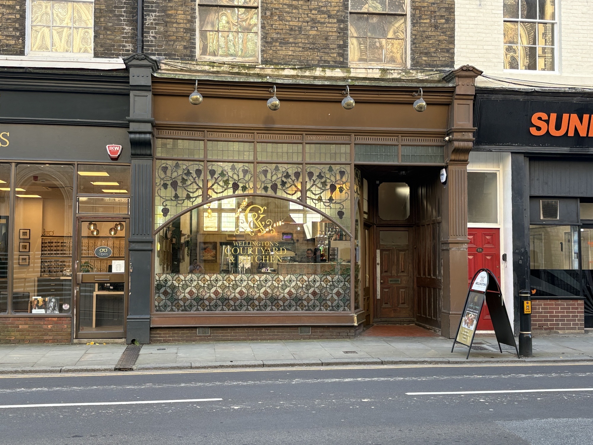 Exterior of a cafe with stained glass window and brown paintwork.