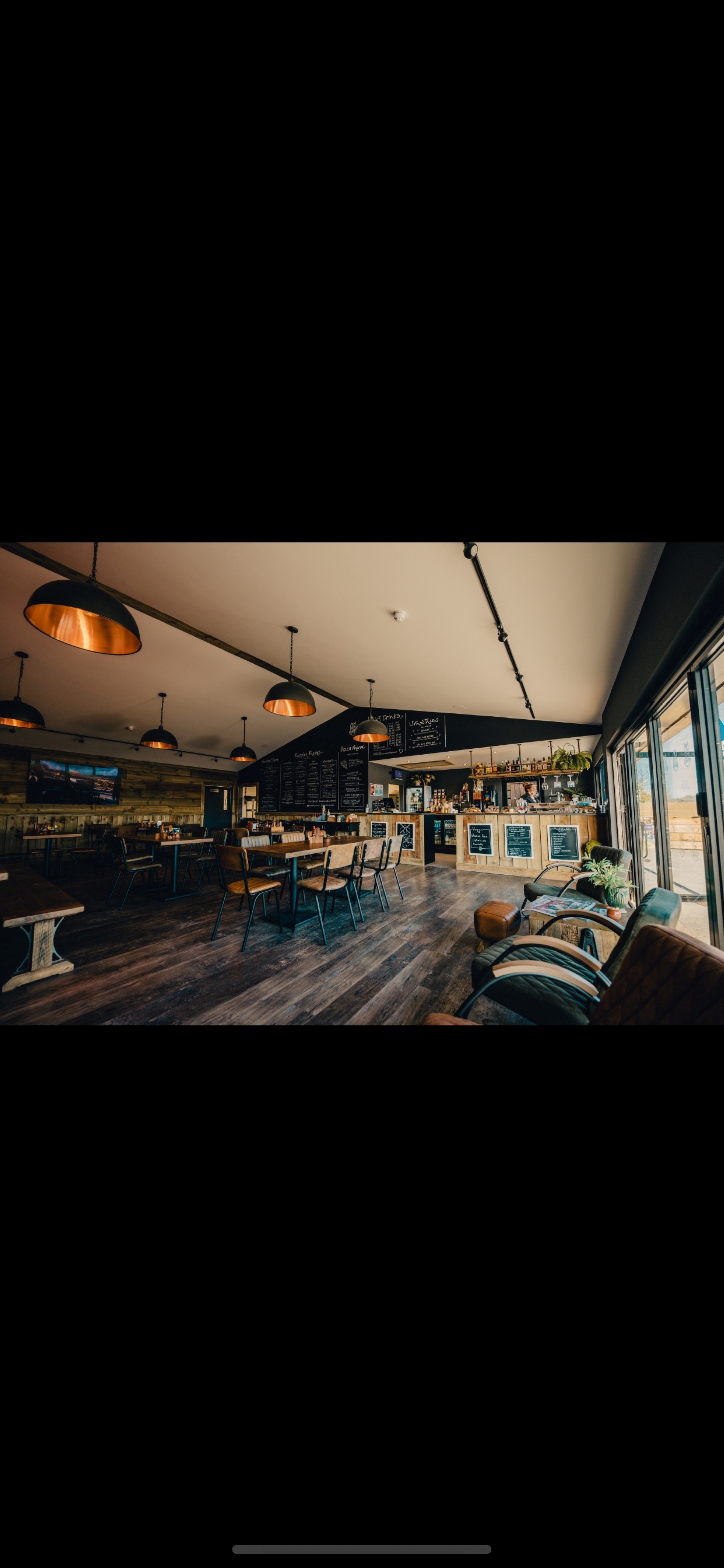 Interior of Whitemills kitchen with wooden floors and walls. Long wooden tables with seating for 6 people