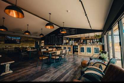 Interior of Whitemills kitchen with wooden floors and walls. Long wooden tables with seating for 6 people